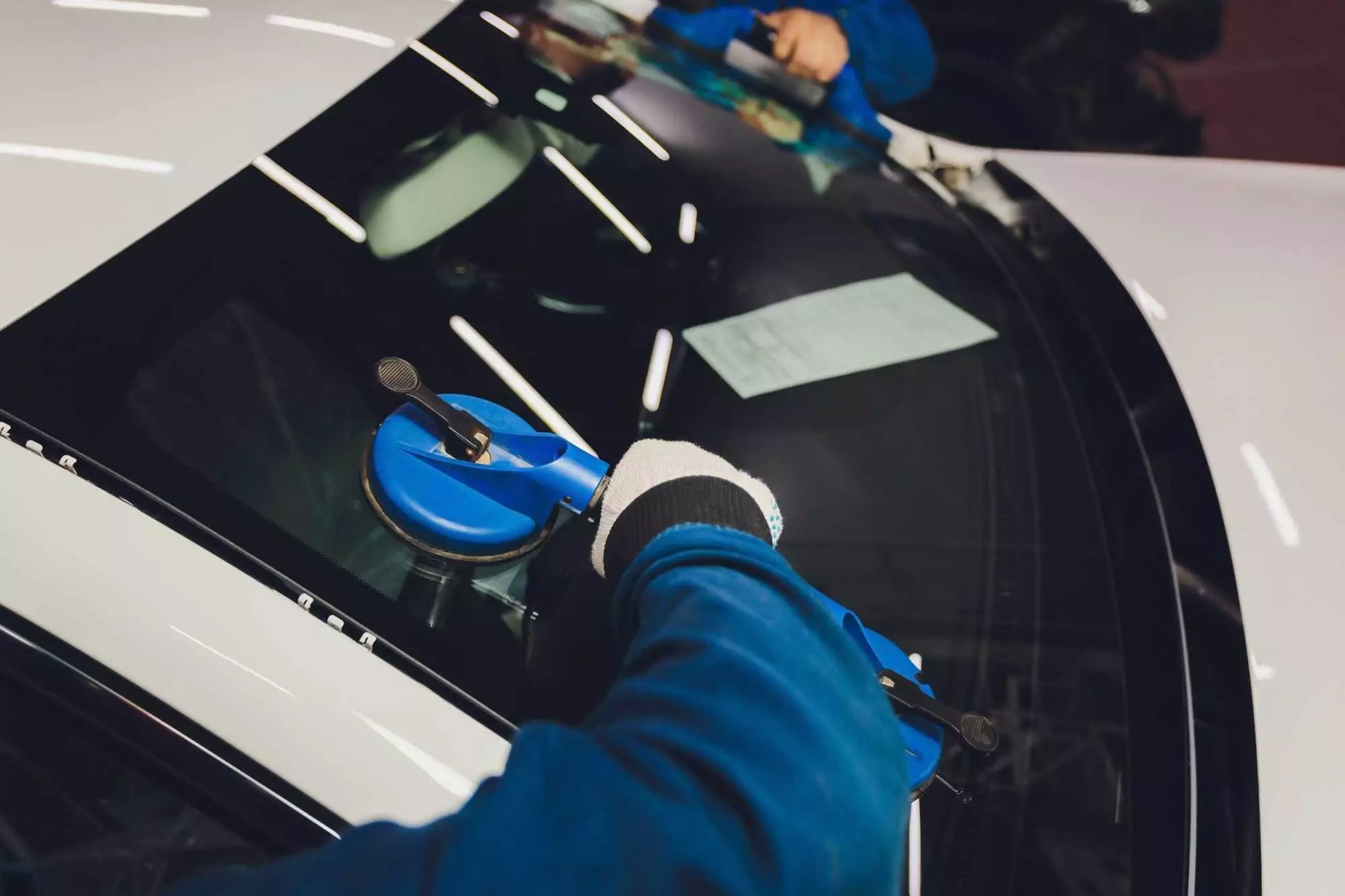 two guys replacing a car windshield